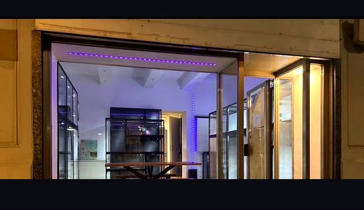 Titan Trade store exterior at night with purple LED lighting and glass vitrines visible from the street